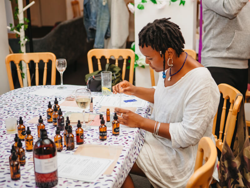 A woman sits at a table, making her own perfume at a workshop